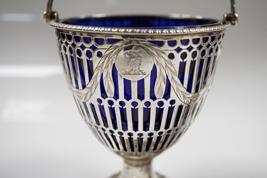 Two George III pierced silver pedestal sugar baskets, with blue glass liners, spiral handle, Burridge Davenport, London, 1777, the other William Plummer, London, 1775, tallest 10.1cm excluding the handle.